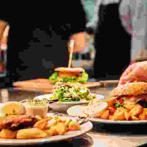 Plates of fresh, flavorful meals including a burger with lettuce, a salad, and golden fries, showcasing High Brew's commitment to memorable dining experiences.