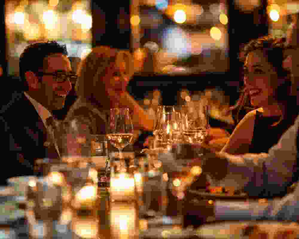 Group of diners enjoying a fine dining experience at High Brew, with elegant table settings, glasses of wine, and a warm, ambient atmosphere.